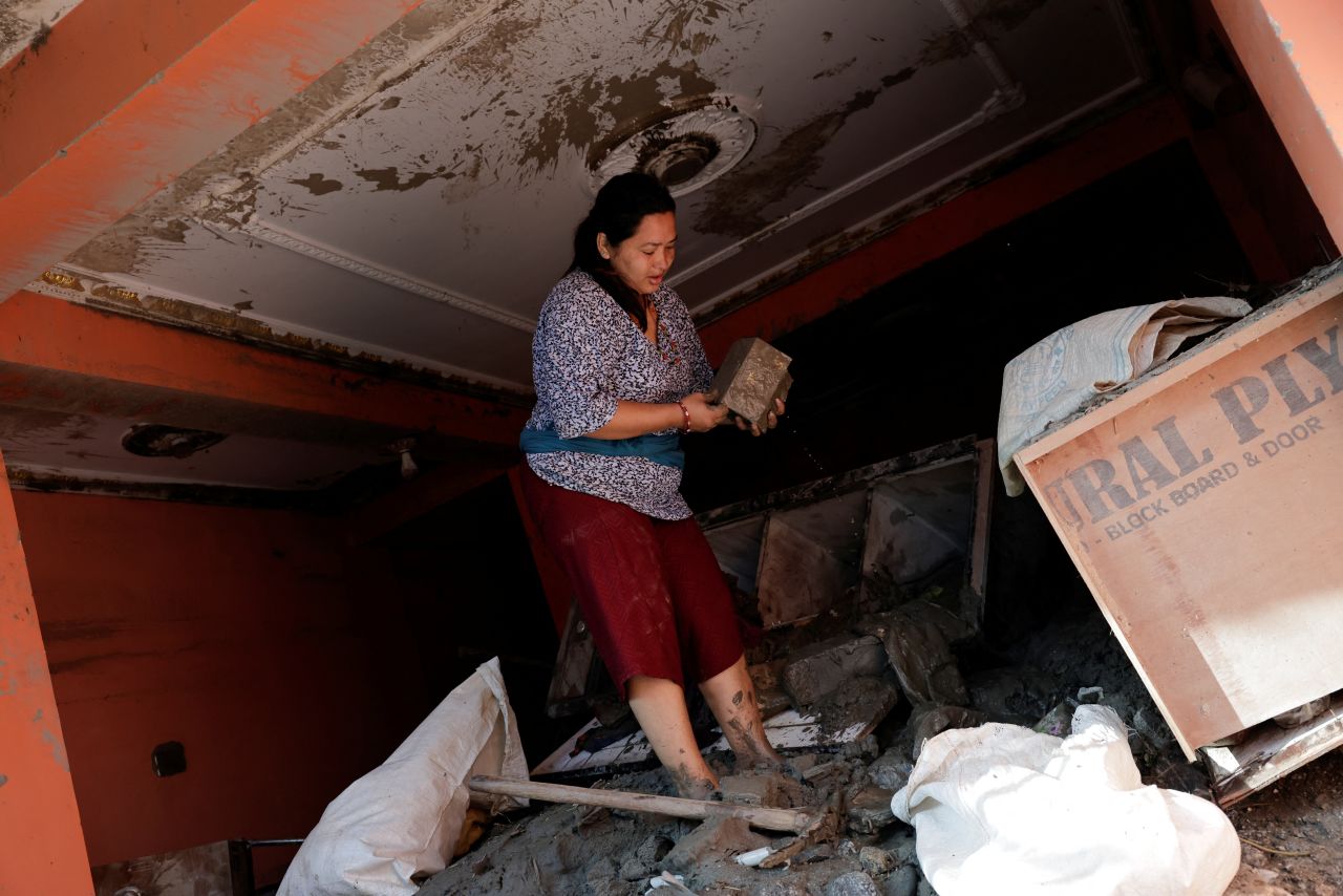 A woman searches for her belongings inside her damaged home following flash floods and a mudslide in Trishuli, Nuwakot district, Nepal, on Friday.