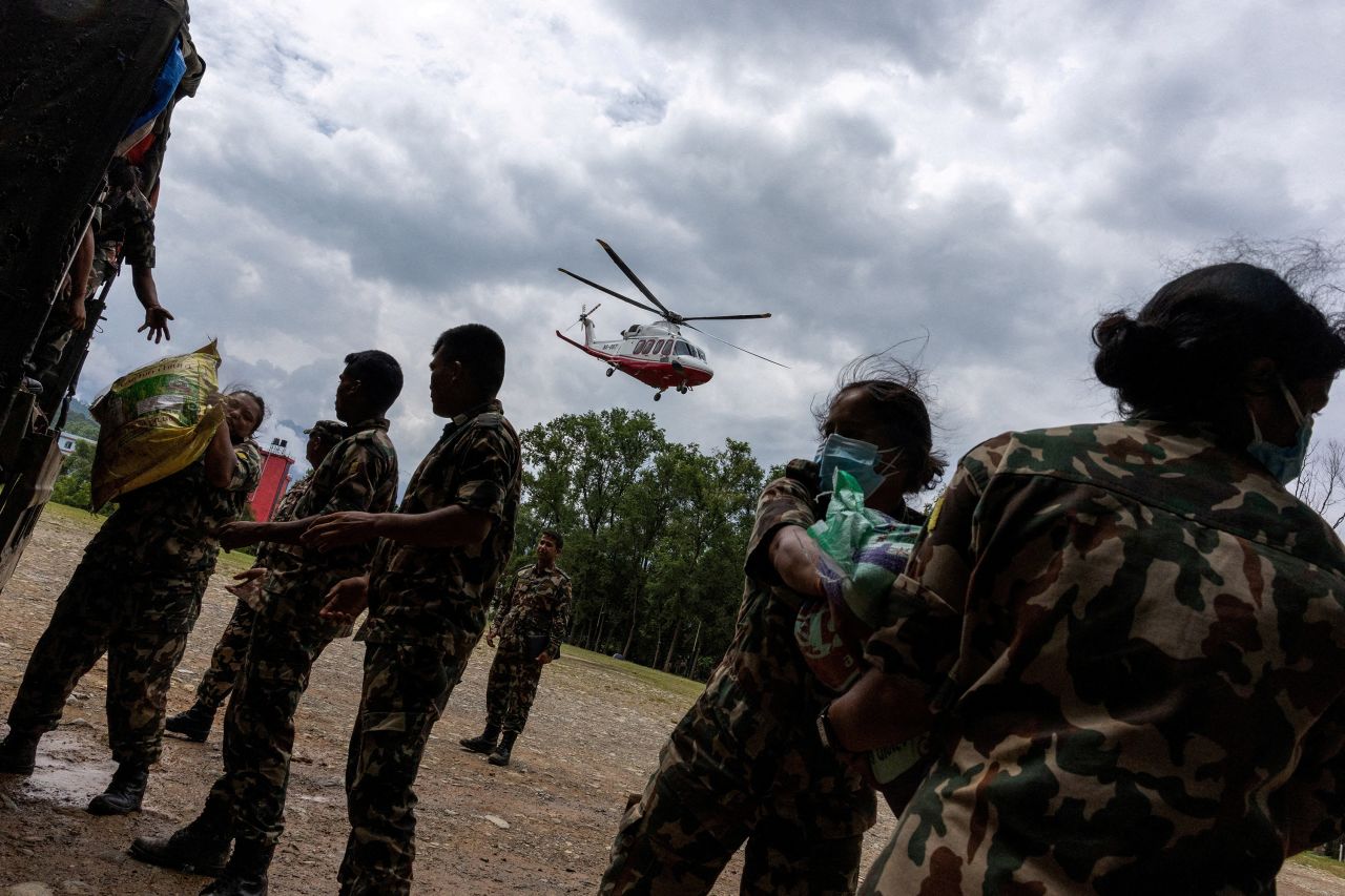 Members of the Nepal Army load relief material as a helicopter containing relief supplies takes off to areas affected by deadly flash floods, at the Maithili Barrack, an army training center, in Trishuli, Nepal, on Saturday.