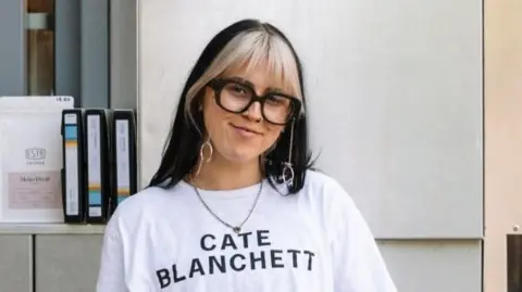 Inbetween Days Photography Frances has black hair with a blonde fringe and she wears a white t-shirt with the words 'CATE BLANCHETT' printed on it. She wears glasses with thick black rims.