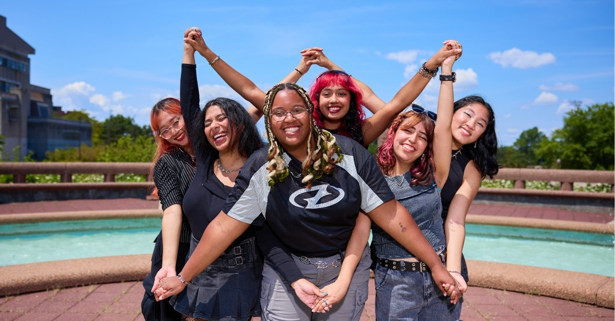 CUNY students form a six-pointed star with their hands on the Queens College campus