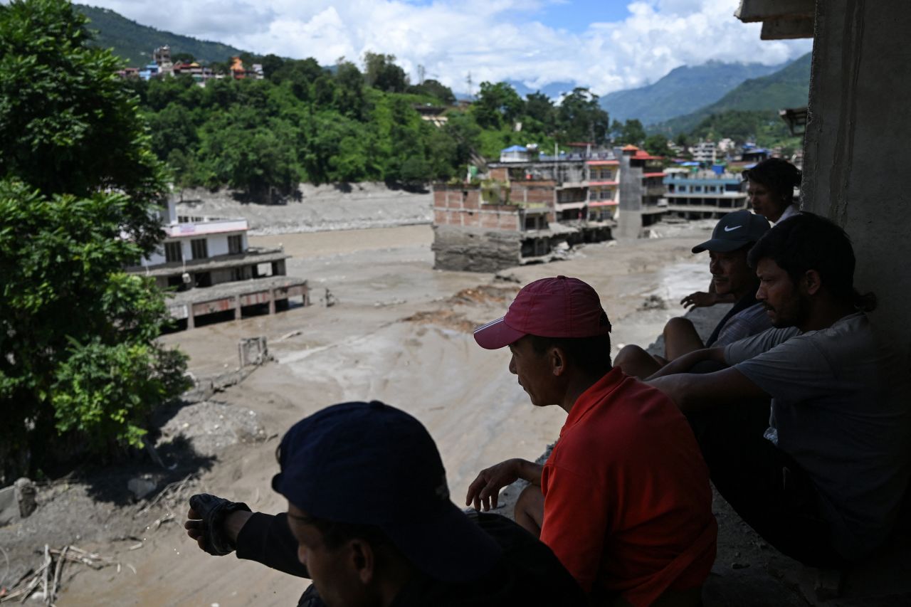 People watch from a rooftop as houses lie deluged in sludge after flash floods at Trishuli in Nepal's Nuwakot district on August 27.