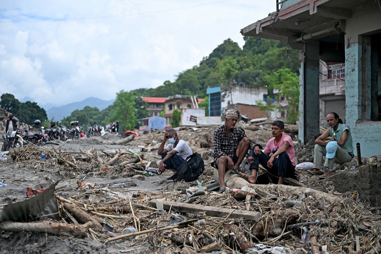 Residents sit beside debris on Monday as they salvage belongings following flash floods at Devighat in Nepal's Nuwakot district.