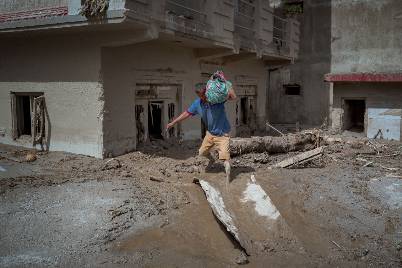 A resident carries belongings he salvaged from his destroyed home following flash floods in Devighat, Nepal, on August 28.