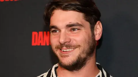 Getty Images RJ Mitte attends a red carpet event in Los Angeles in 2023. He is smiling.